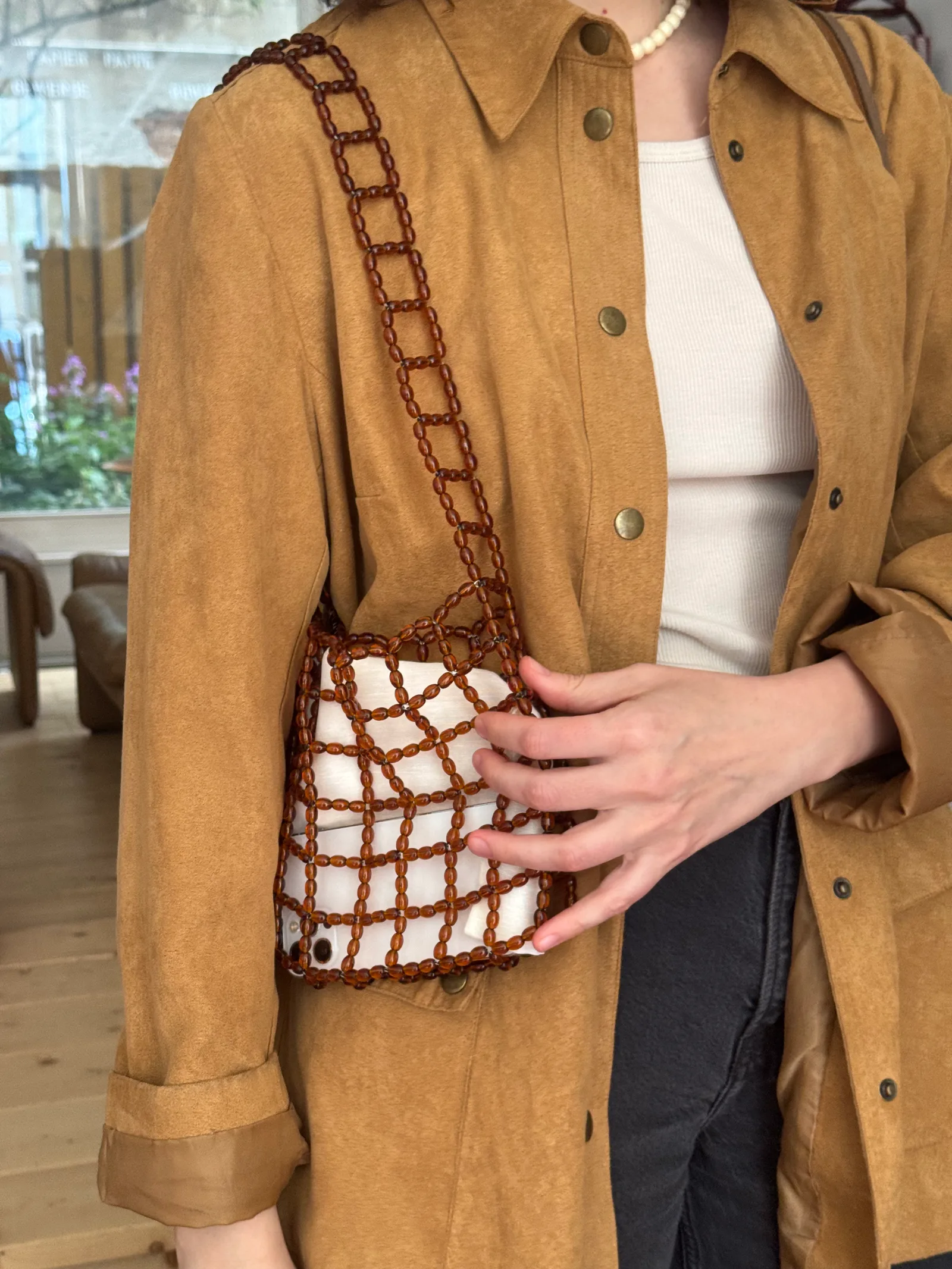 A compact shoulder bag made of interlinked brown beads with a structured, grid-like design. Lightweight yet durable, it fits essentials and adds a clean, modern accent to everyday outfits.

Approx. 22 cm x 17 cm 
Strap length - 31 cm

Brown glass beads
Includes a removable light coloured pouch

We recommend carrying only essentials such as your phone, lipstick, wallet and sunglasses. Since we use metal thread for weaving, we advise avoiding direct contact with water.

Handcrafted in Kyiv
