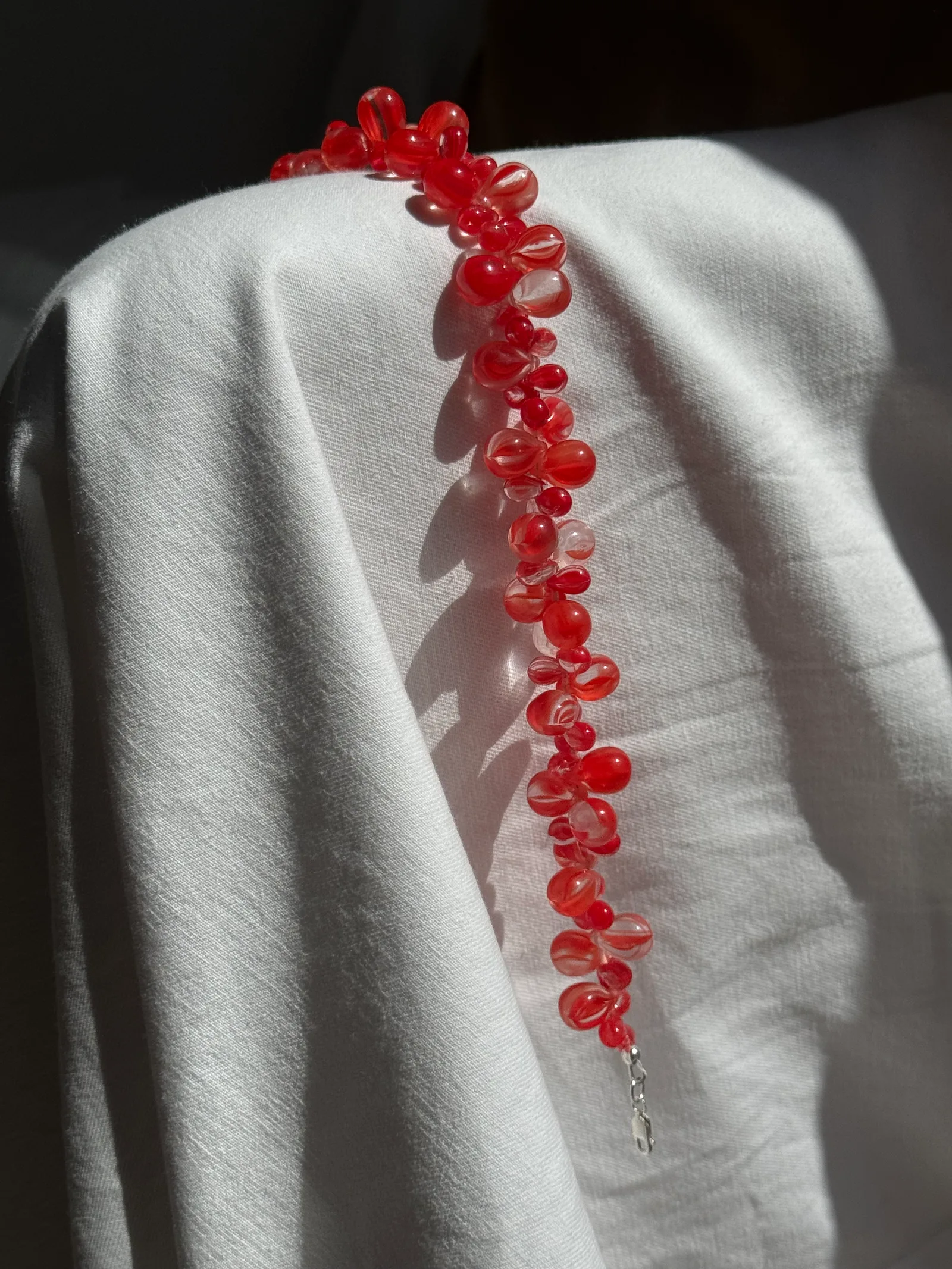 A bold yet delicate statement necklace handcrafted with translucent red glass beads in organic petal-like shapes. Lightweight, playful, and luminous.

Glass beads 
Sterling silver hardware

43 cm length

Each piece is uniquely arranged, so the necklace may vary slightly from the one pictured.

Handcrafted in Berlin