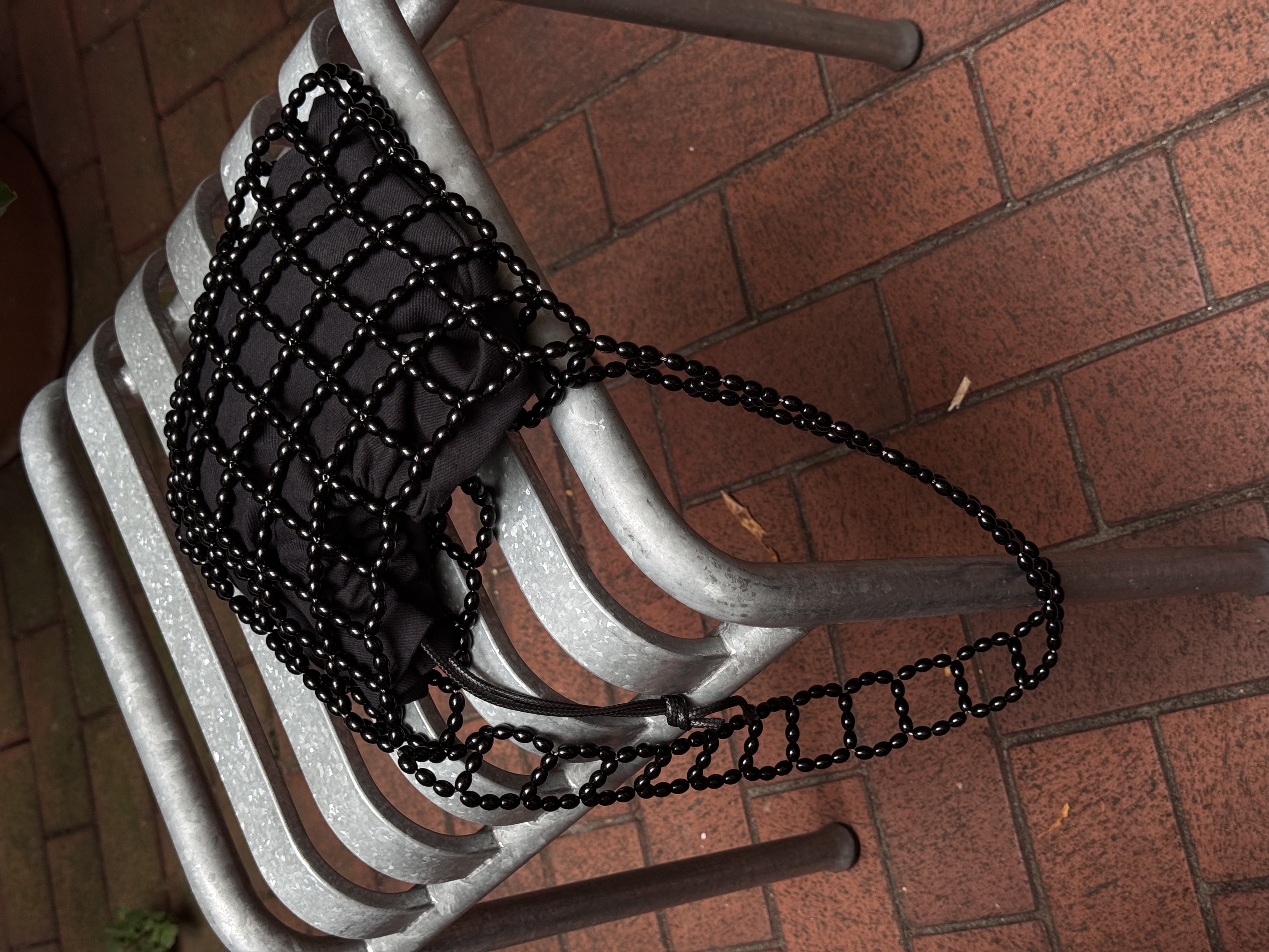 A compact shoulder bag made of interlinked black beads with a structured, grid-like design. Lightweight yet durable, it fits essentials and adds a clean, modern accent to everyday outfits.

Approx. 21 cm x 17 cm
Strap length - 28 cm

Black glass beads
Includes a removable black cotton pouch

We recommend carrying only essentials such as your phone, lipstick, wallet and sunglasses. Since we use metal thread for weaving, we advise avoiding direct contact with water.

Handcrafted in Kyiv

